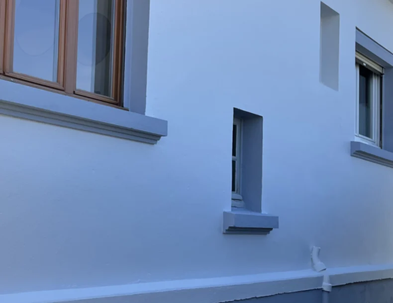 Après travaux : Des murs blancs uniformes, soulignés par les appuis de fenêtre et le soubassement gris.